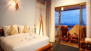 A hotel room with a large bed, a wooden headboard, and a balcony with wicker furniture. - Haadson Resort (Ko Pha-ngan)