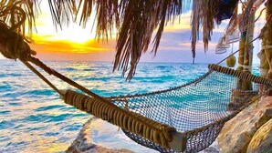 A hammock tied between rocks overlooking a beach with a sunset in the background. - Haadson Resort (Ko Pha-ngan)