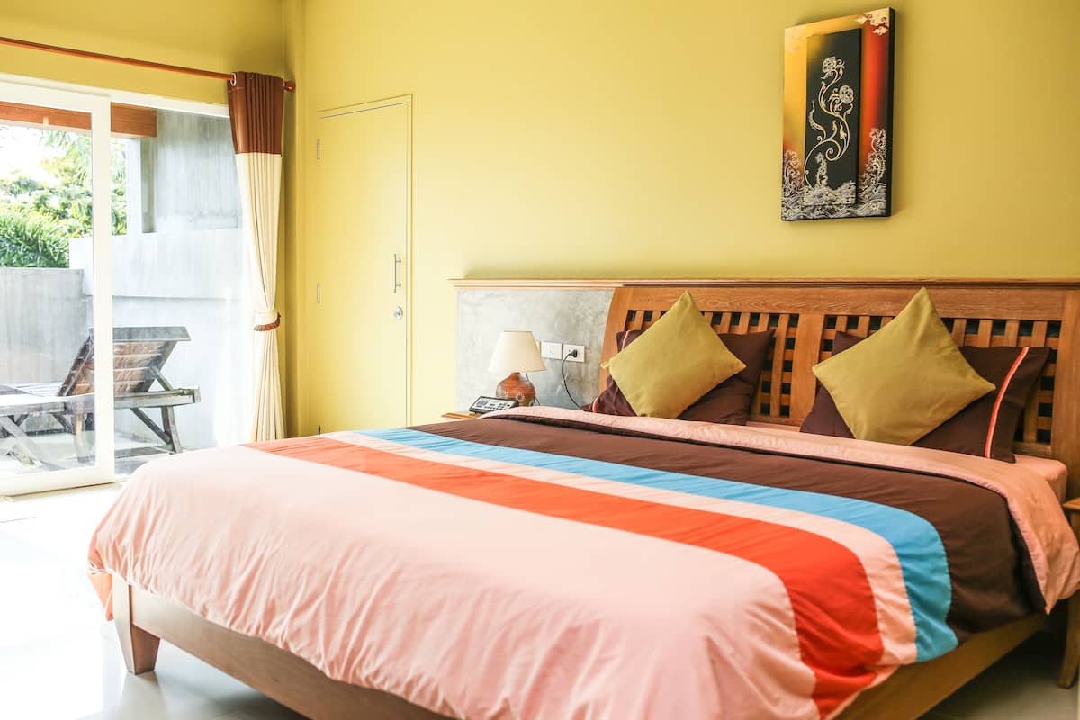 A bedroom with a bed, pillows, a nightstand, and a wall-mounted lamp.