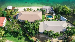 An aerial view of a resort with multiple buildings, a swimming pool, and a beach.