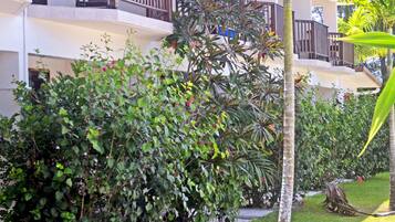 A hotel with multiple balconies, lush greenery, and a well-maintained lawn.