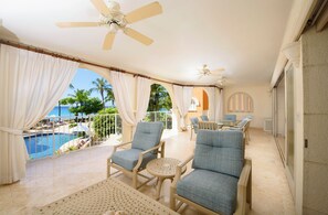 A sunlit patio with a pool view, cushioned seating, and ceiling fans. - Saint Peter's Bay (Speightstown)