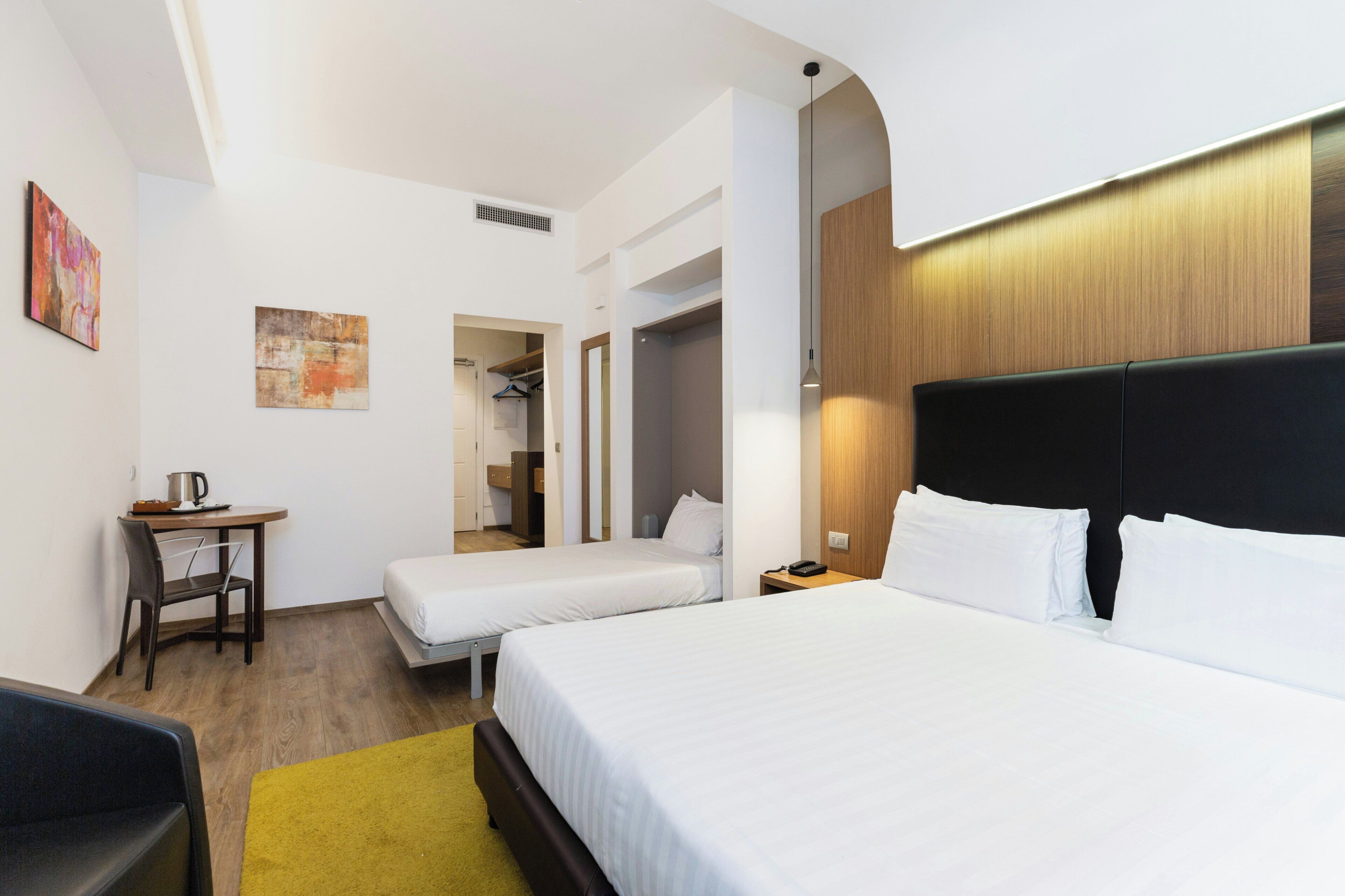 Habitació d'hotel amb dos llits, un escriptori, una cadira i un penjallabecs.