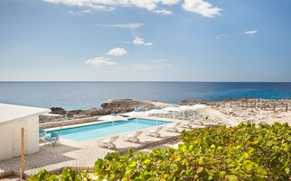 Una piscina al aire libre, sombrillas, tumbonas