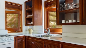 A kitchen with wooden cabinets, a white countertop, a sink, and a stove.