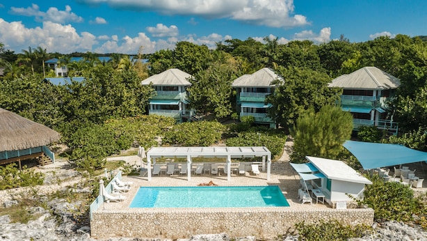 A resort with a swimming pool, multiple villas, and a beach area.