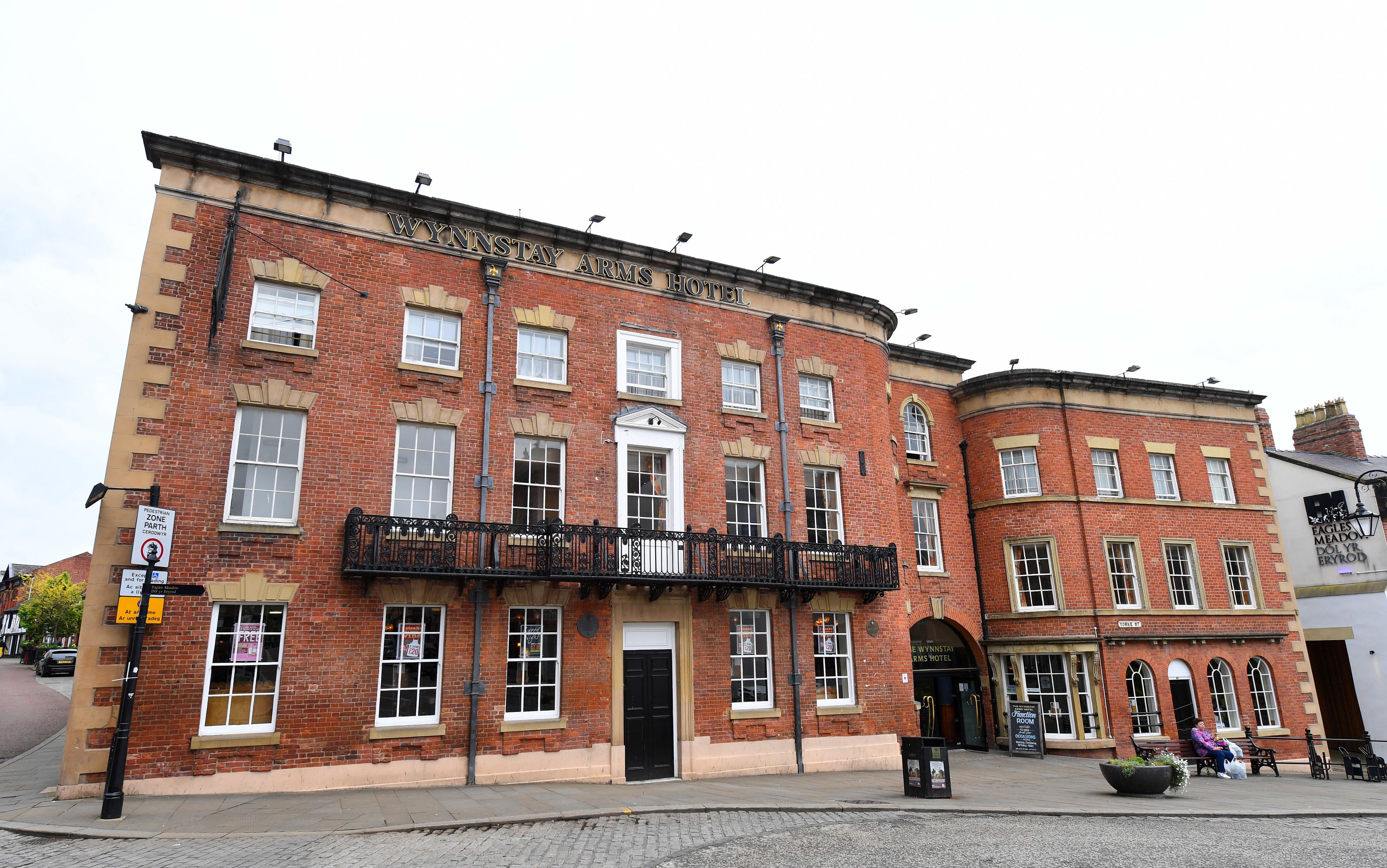 A red brick building with a black balcony and a sign reading "WYNNSTAY ARMS HOTEL".