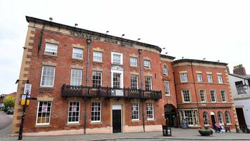 Un edificio de ladrillo rojo con un balcón negro y un letrero que dice "WYNNSTAY ARMS HOTEL".