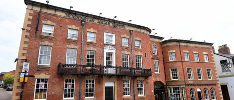 Un edificio de ladrillo rojo con un balcón negro y un letrero que dice "WYNNSTAY ARMS HOTEL".