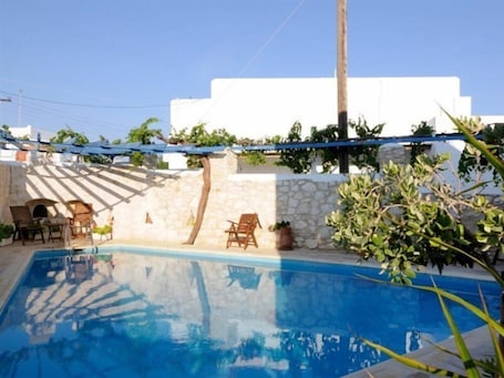 Una piscina al aire libre, sombrillas, sillones reclinables de piscina