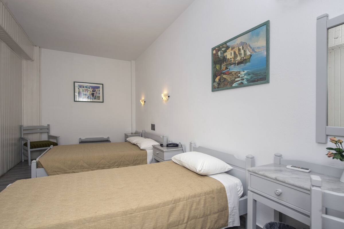 A hotel room with two beds, a bathroom with a marble sink, and a painting on the wall.