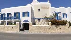 Un edificio blanco con contraventanas azules y fachada de piedra.