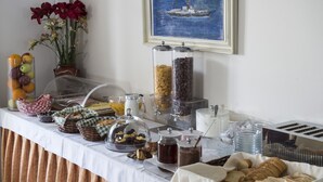 Una mesa de buffet con diferentes alimentos y un cuadro de un barco en la pared.