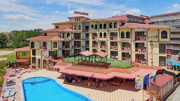 Un hotel con varios balcones, piscina y zonas de estar al aire libre.