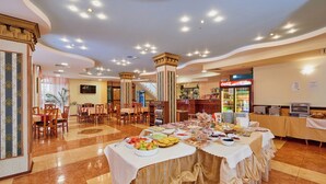 A buffet setup with various food items, a Coca-Cola refrigerator, and a seating area with tables and chairs. - Smolian (Nessebar)