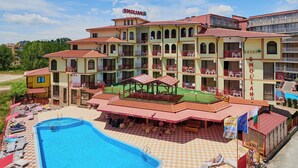 A hotel with multiple balconies, a swimming pool, and outdoor seating areas. - Smolian (Nessebar)