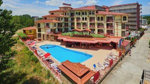 A hotel with a swimming pool, outdoor seating, and multiple balconies. - Smolian (Nessebar)