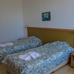 A room with two beds, each with patterned bedding, a small bedside table, a wall-mounted lamp, and a framed picture on the wall. - Trakia Garden (Sunny Beach)