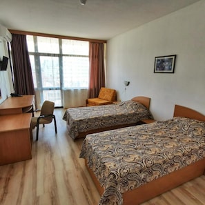 A hotel room with two beds, a desk, a chair, and a window with curtains. - Trakia Garden (Sunny Beach)