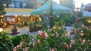 Un restaurante con terraza y un jardín al frente.
