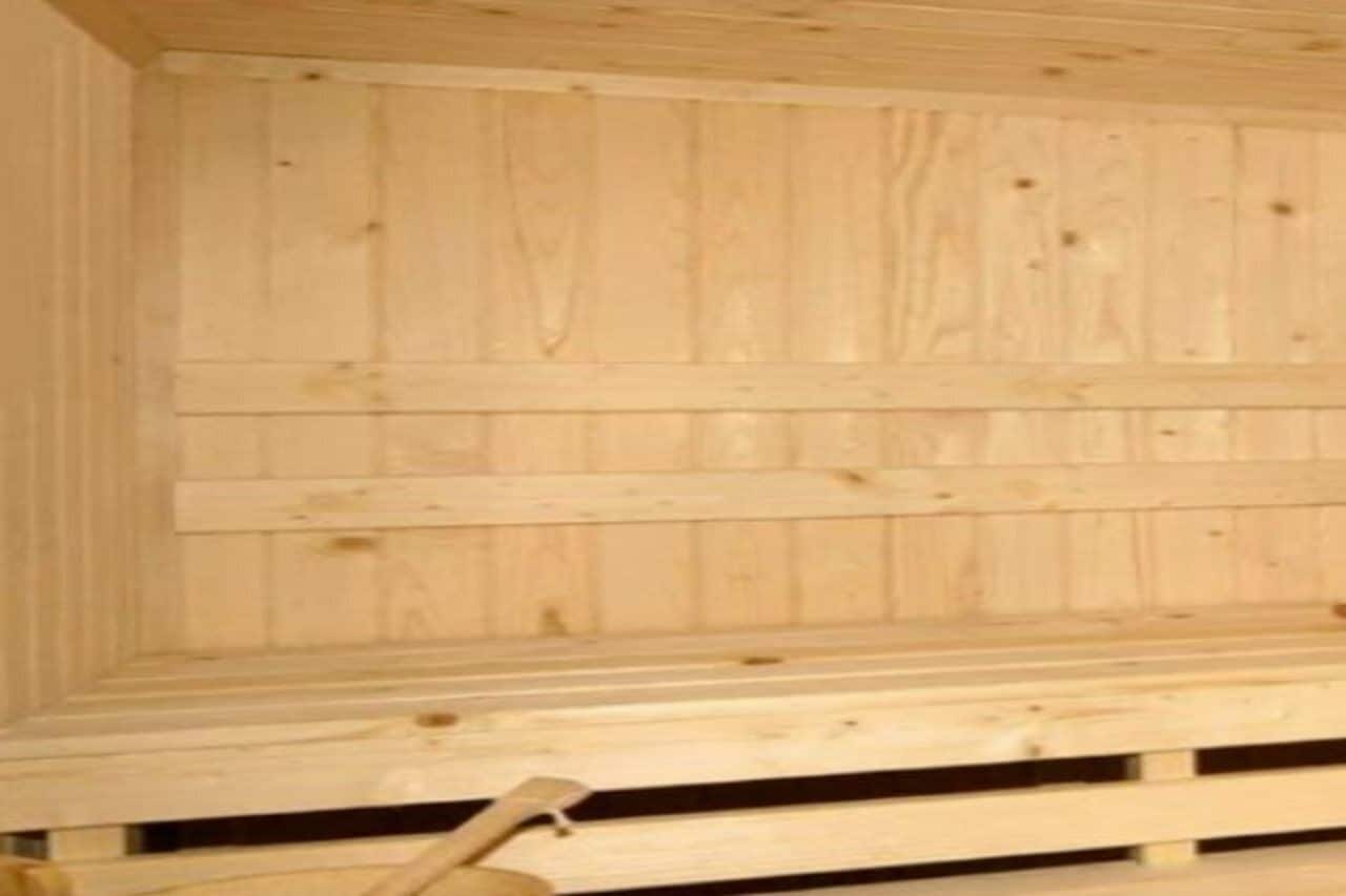 Ein Holzhütten-Interieur mit schrägverdeckter Decke und einer Bank an der Wand.