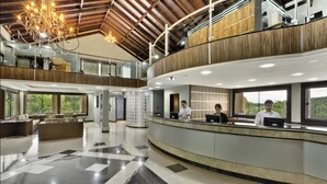 Un hall d’entrée spacieux, doté d’un comptoir d’enregistrement, d’un lustre et d’un plafond haut orné de poutres en bois.
