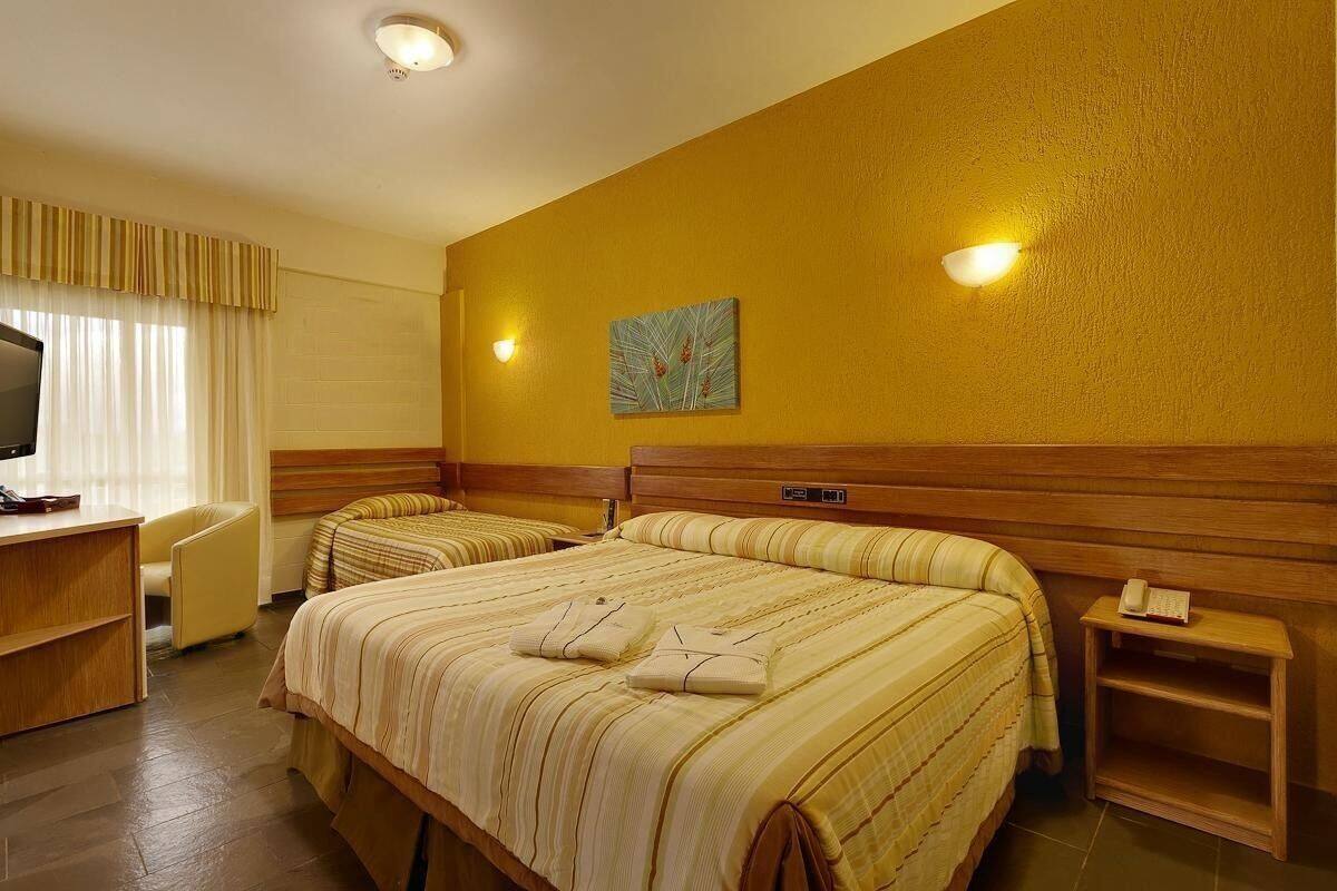 Habitación de hotel con dos camas, un escritorio, una silla y un cuadro en la pared.