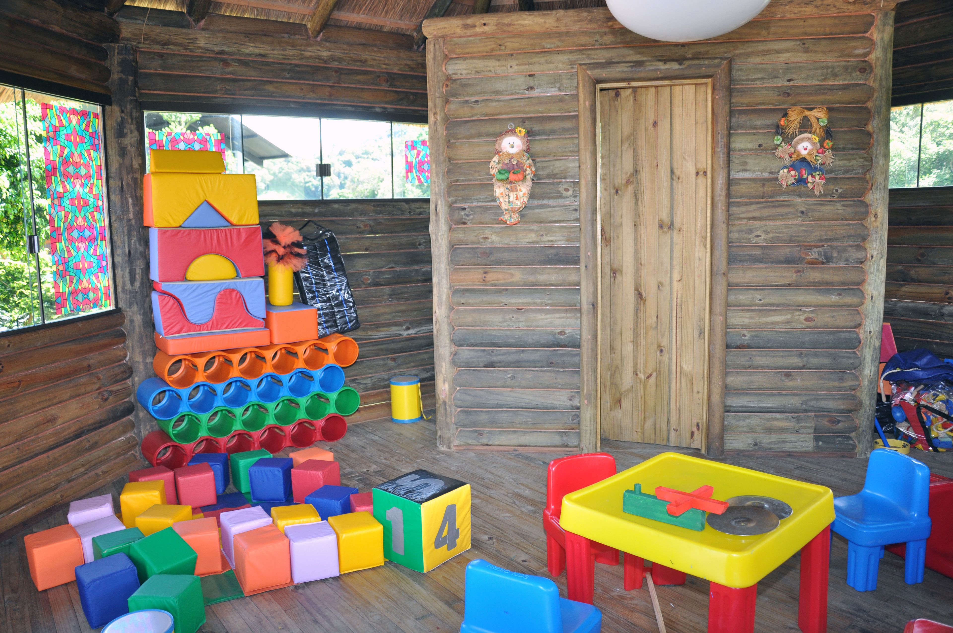 Interior de una cabaña de madera con bloques de construcción de colores, una mesita y sillas.
