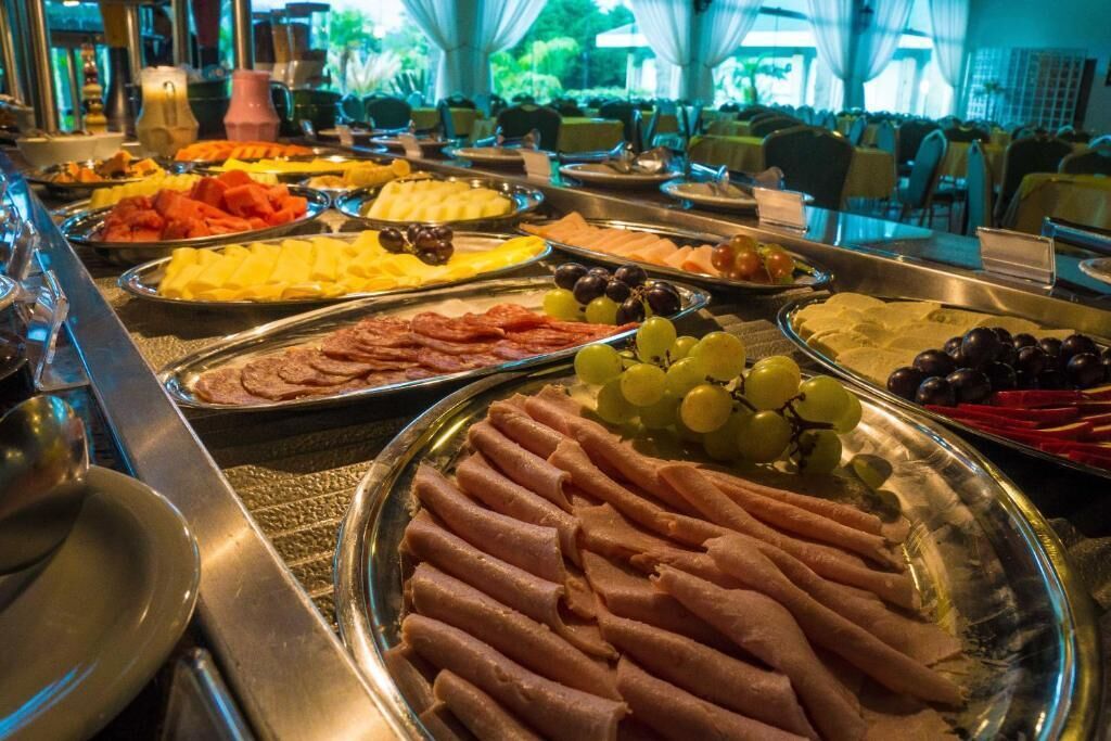 A buffet with various food items including meats, cheeses, fruits, and vegetables.
