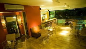 A spacious indoor area with a bar, seating, and a view of a pool. - Hotel Villaoeste (Mossoro)