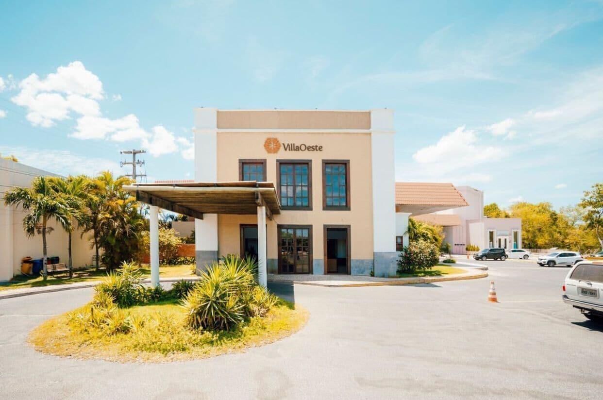 Hotel VillaOeste com fachada moderna, entrada coberta e área de estacionamento.