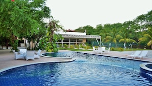 A swimming pool with lounge chairs and a building in the background. - Hotel Villaoeste (Mossoro)