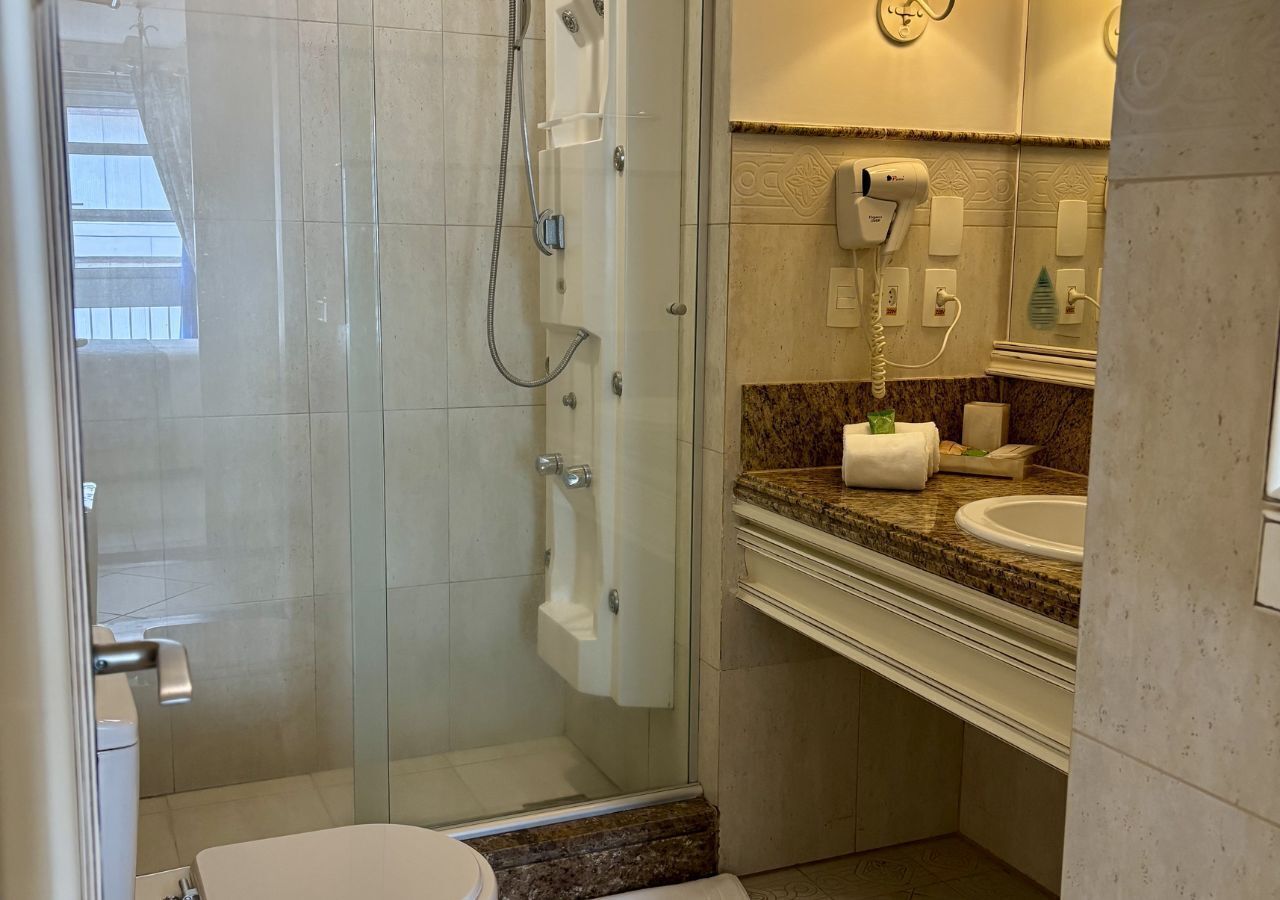 Un bagno moderno con doccia vetro, un water e un lavabo con piano in marmo.