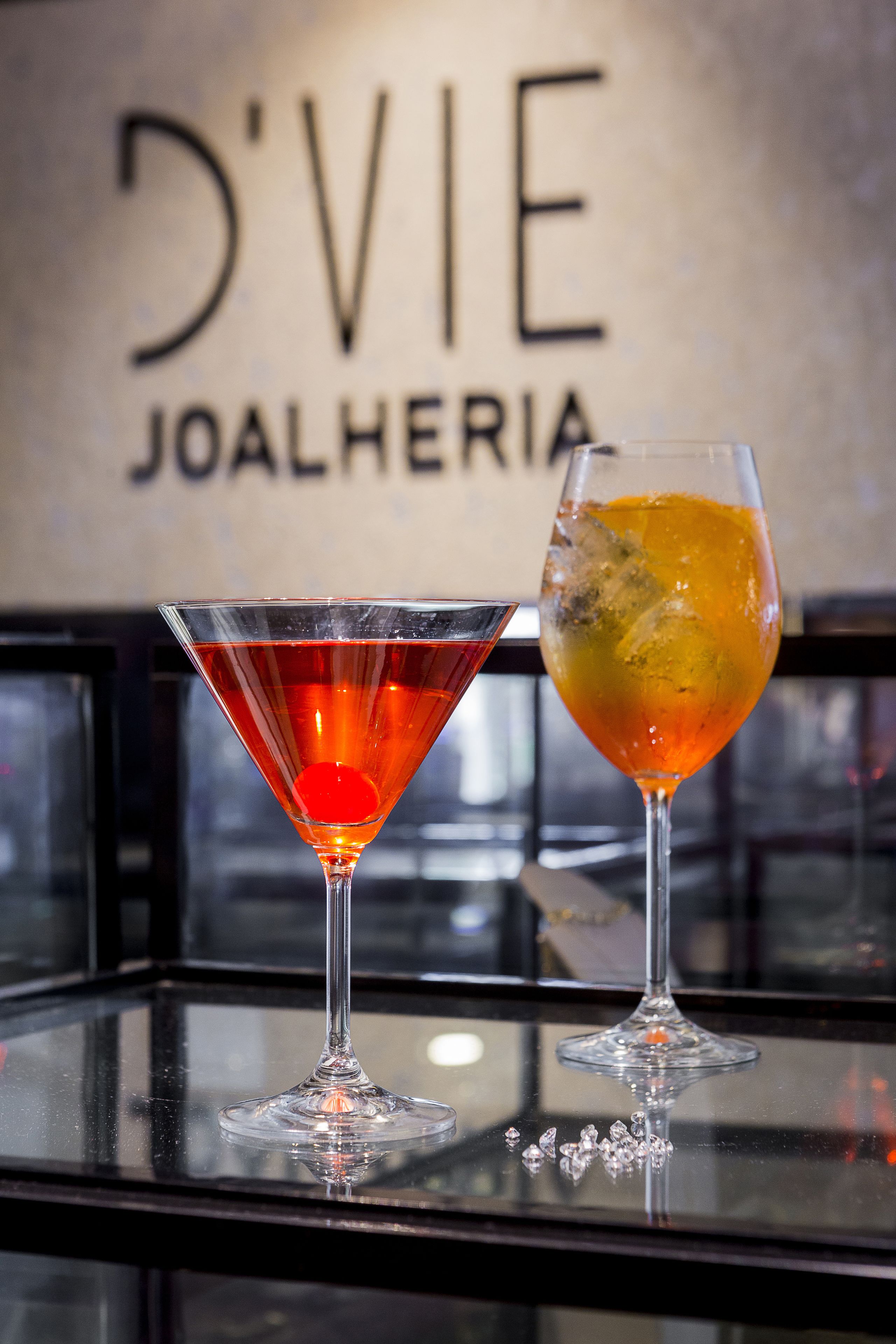 Two cocktails on a bar counter with a sign in the background.