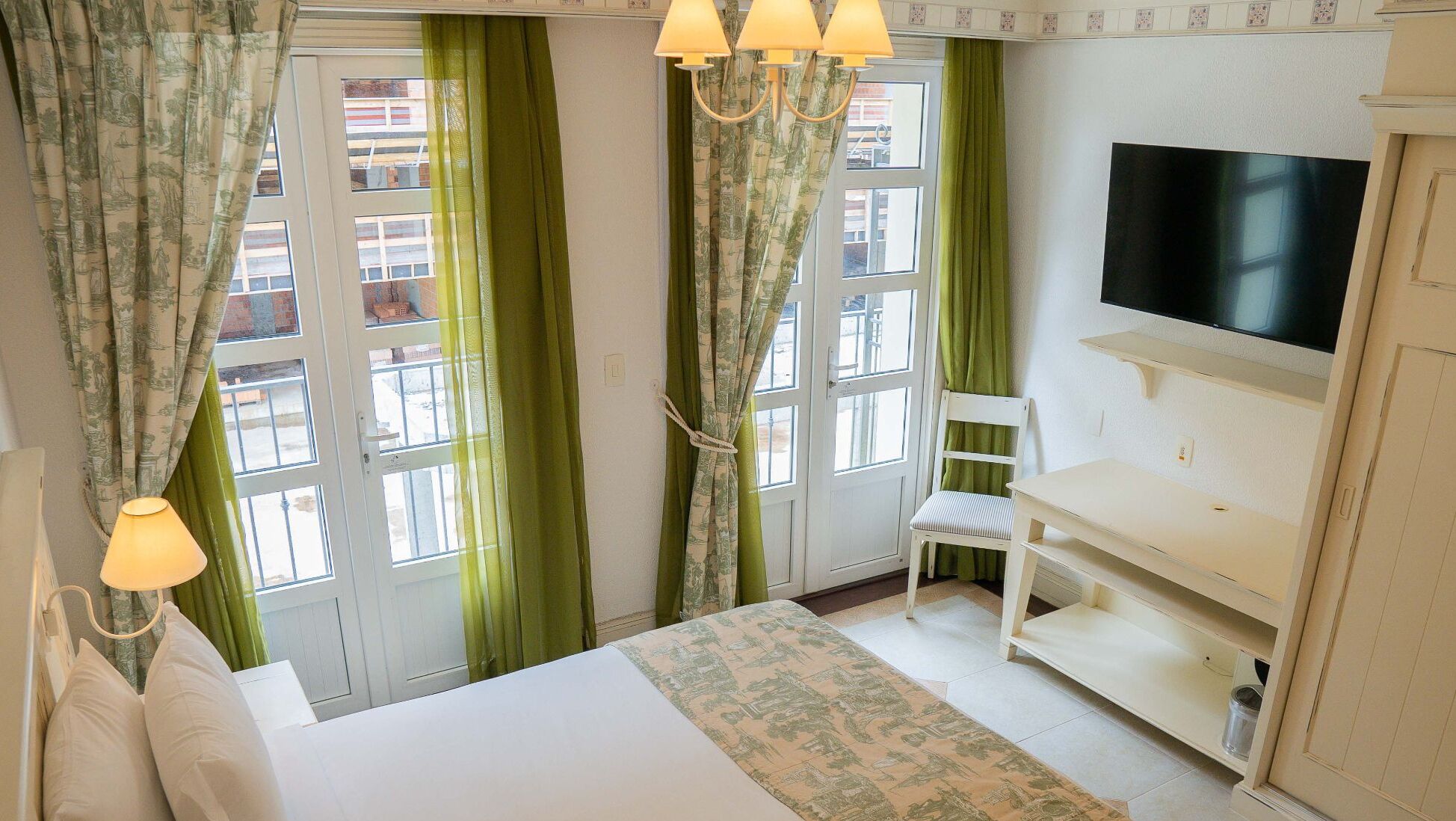 Una habitación de hotel con cama, televisión, silla y escritorio.