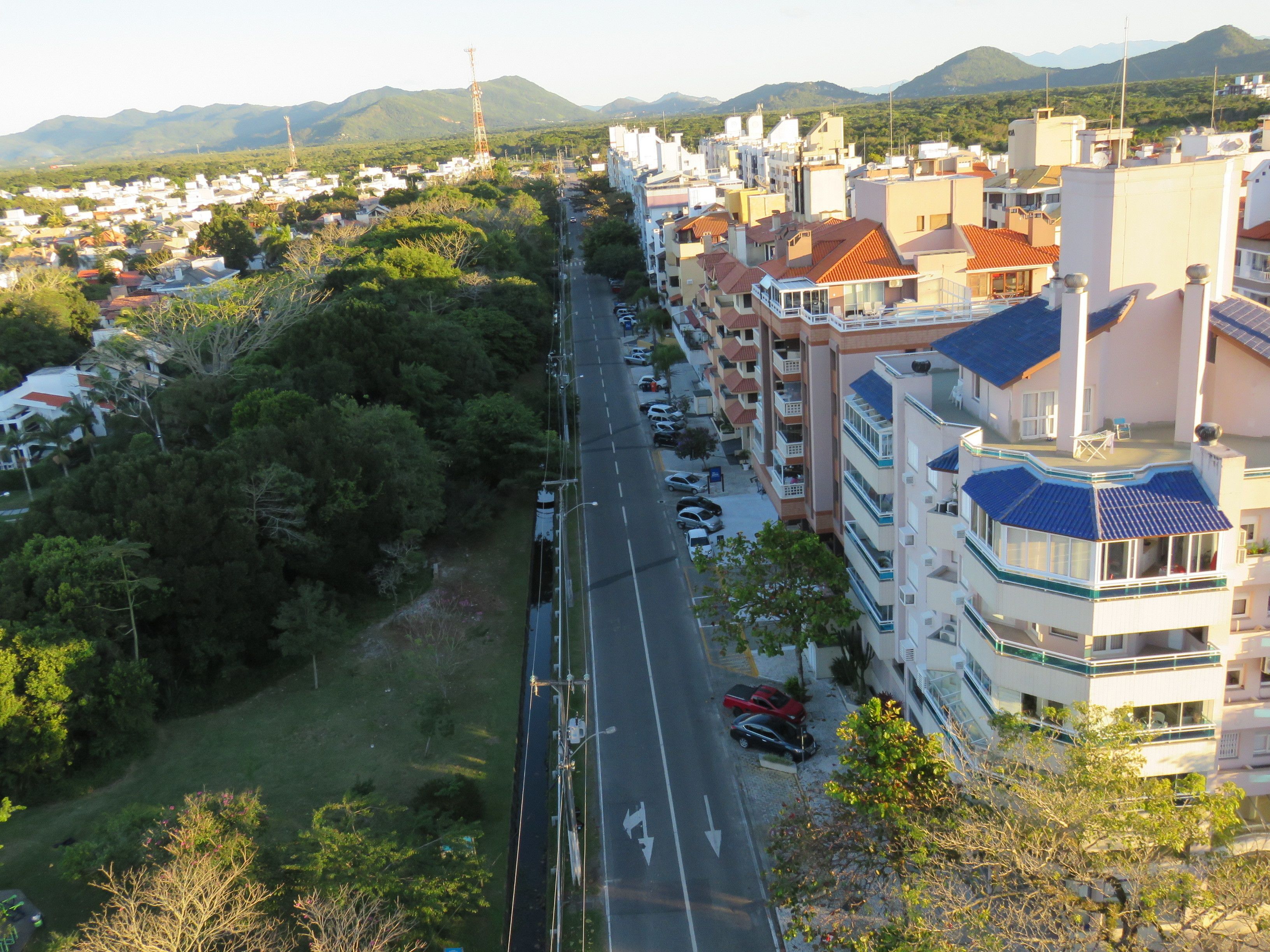 A multi-story hotel with balconies, a road in the foreground, and a mountainous backdrop.