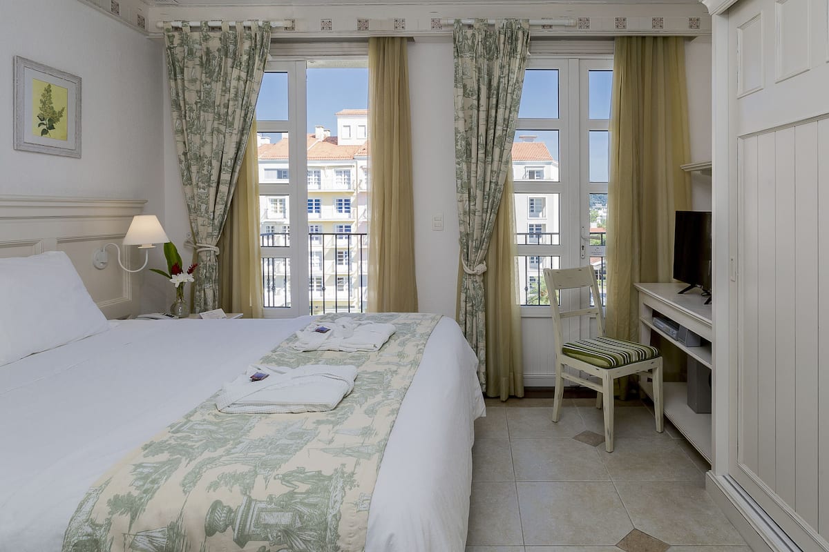 A hotel room with a bed, a desk, a chair, and a TV.