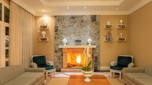 Una sala de estar acogedora con chimenea de piedra, dos sillones, una mesa de centro de madera y una planta en maceta.