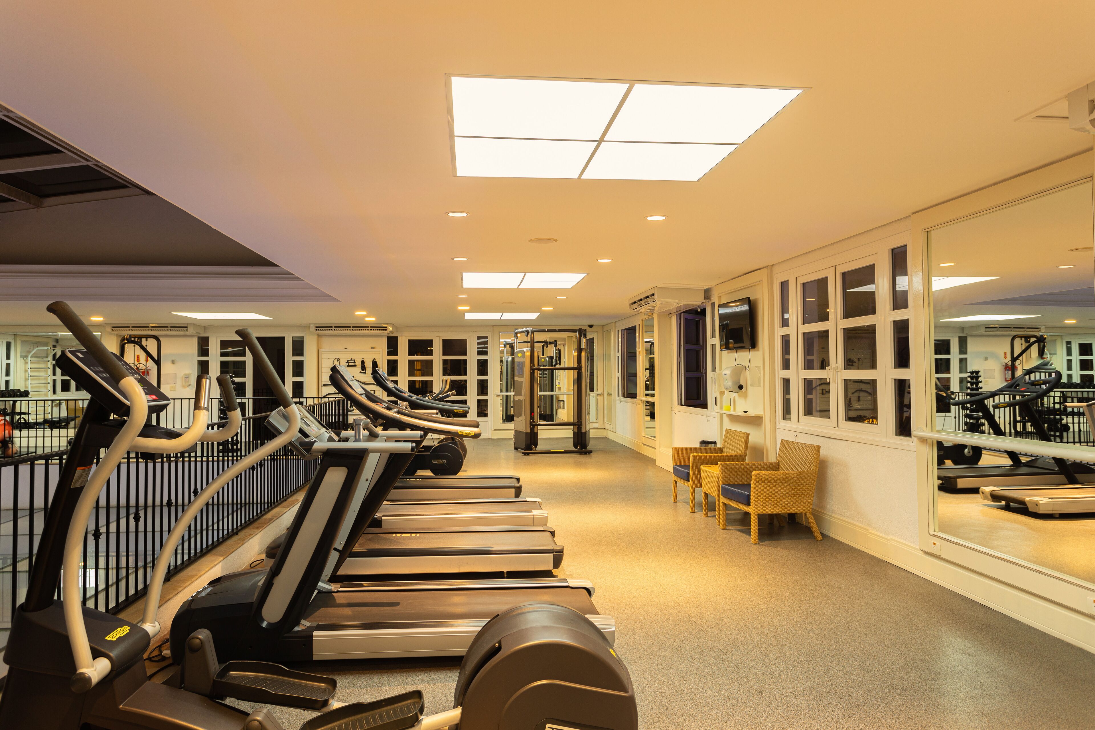 Et fitnesscenter med løbebånd, træningsudstyr og store vinduer.