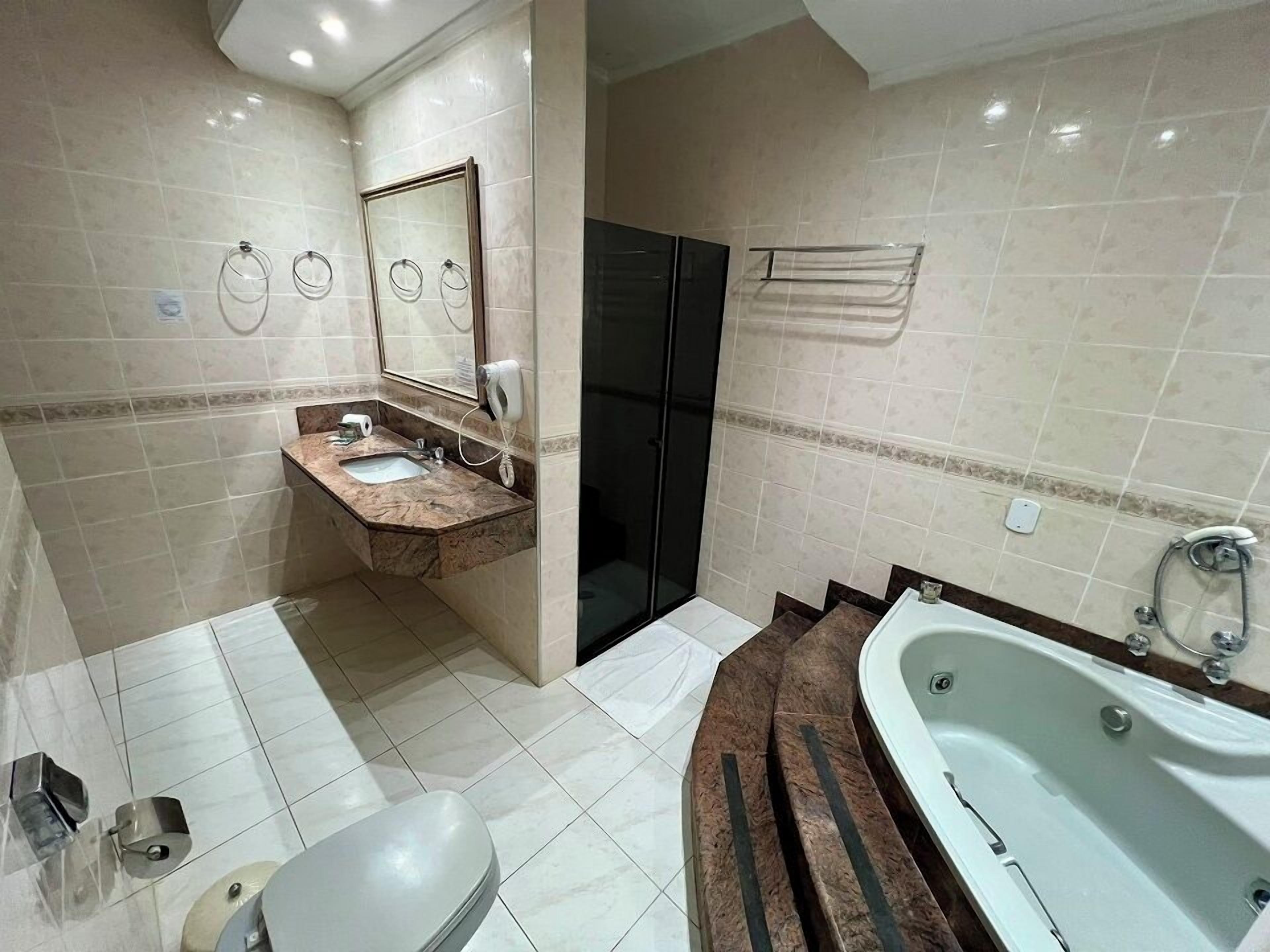 Un baño moderno con lavamanos de mármol, bañera y retrete.