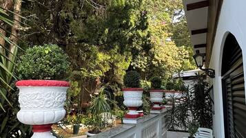 Un espacio al aire libre techado con piso de baldosas, barandillas blancas y plantas en macetas.