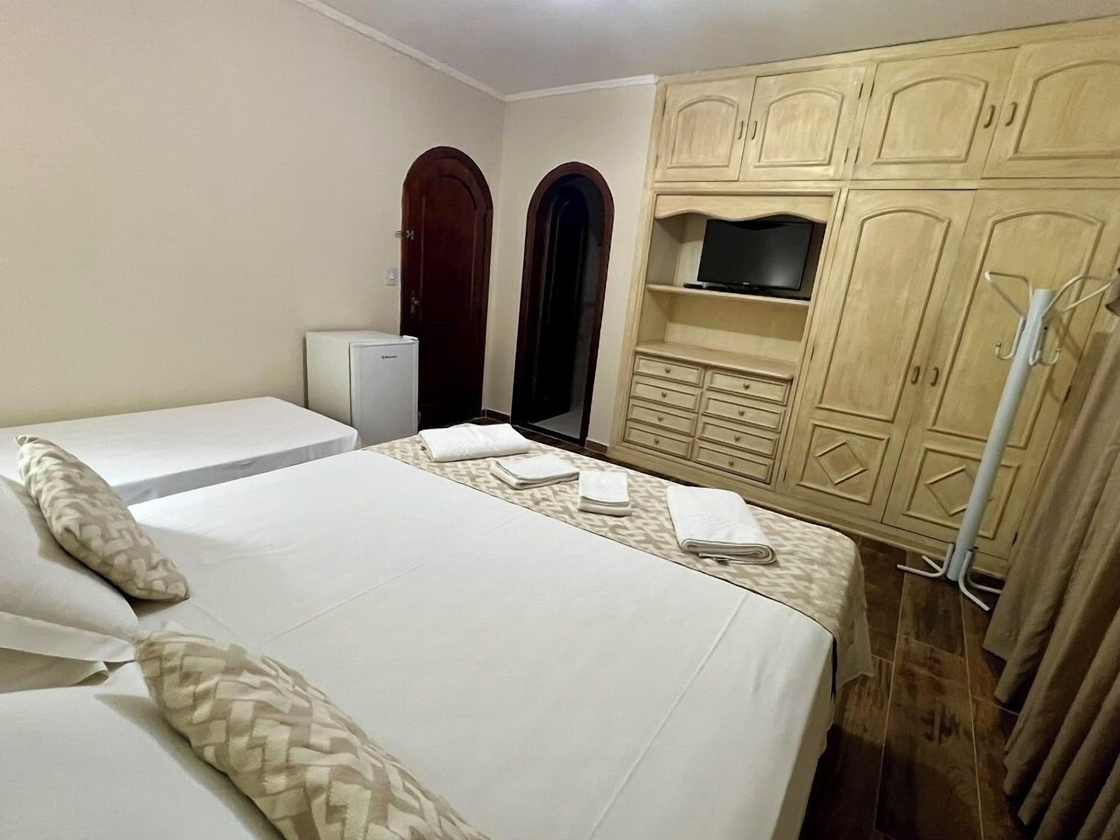 Habitación de hotel con dos camas, un armario, un televisor y un radiador.