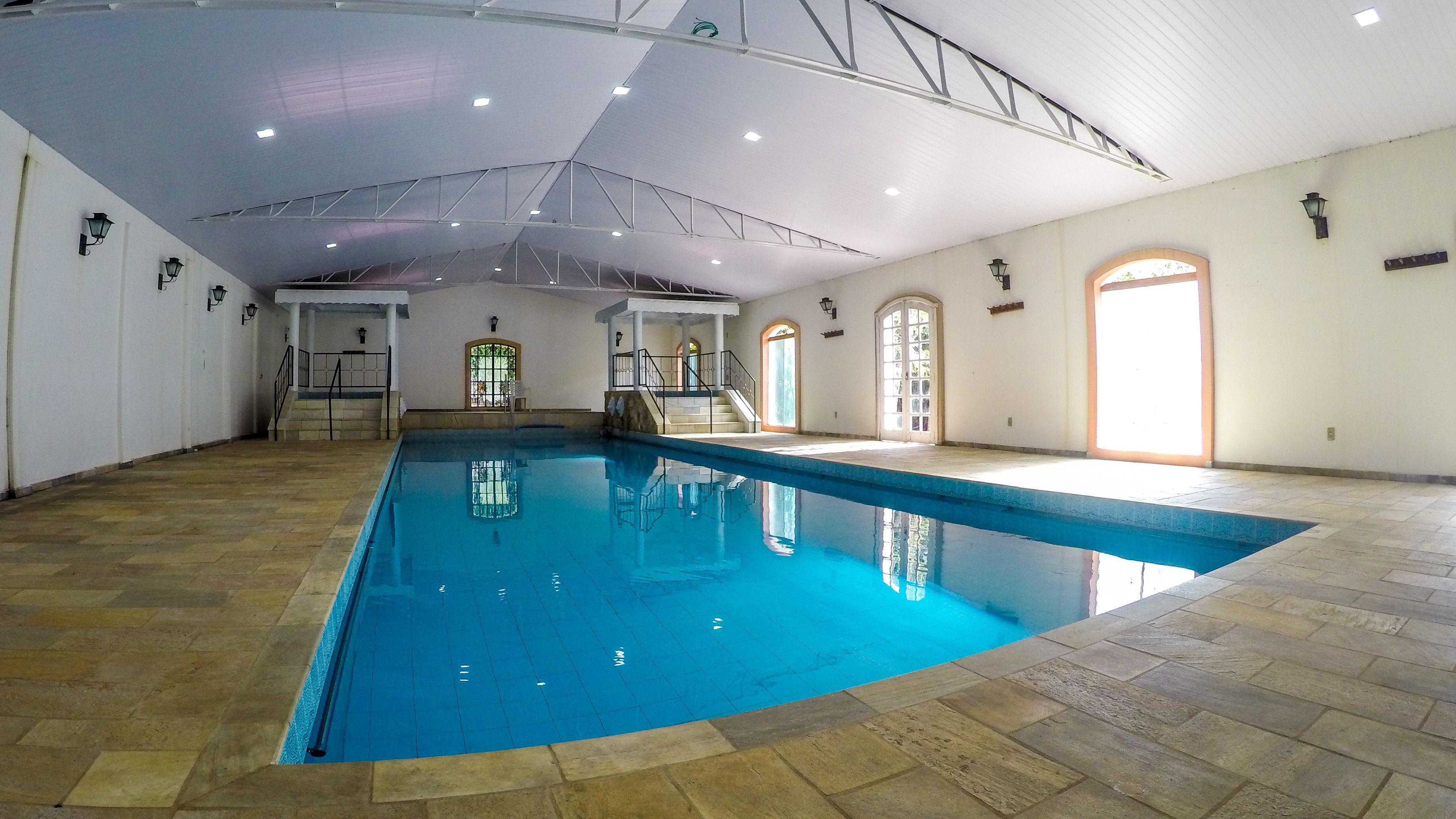 A large indoor swimming pool with tiled flooring and a high ceiling.