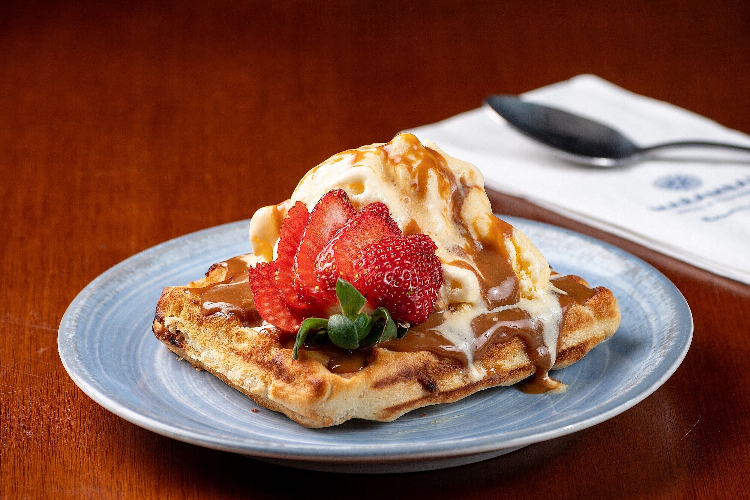 A plate with a dessert topped with strawberries and caramel sauce.