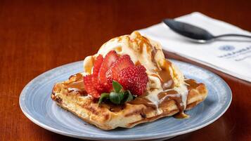 A plate with a dessert topped with strawberries and caramel sauce.