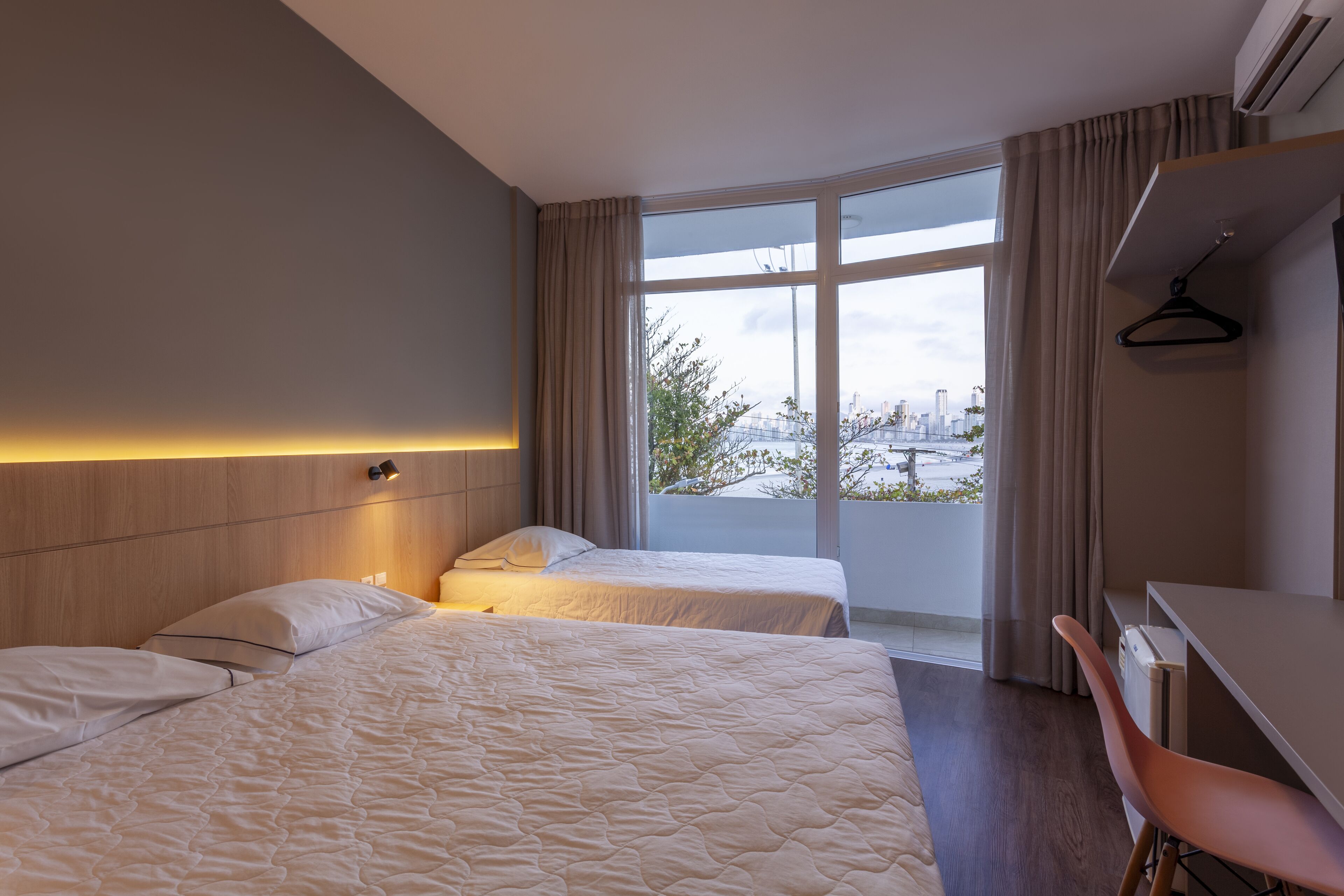 A hotel room with two beds, a desk, and a chair.