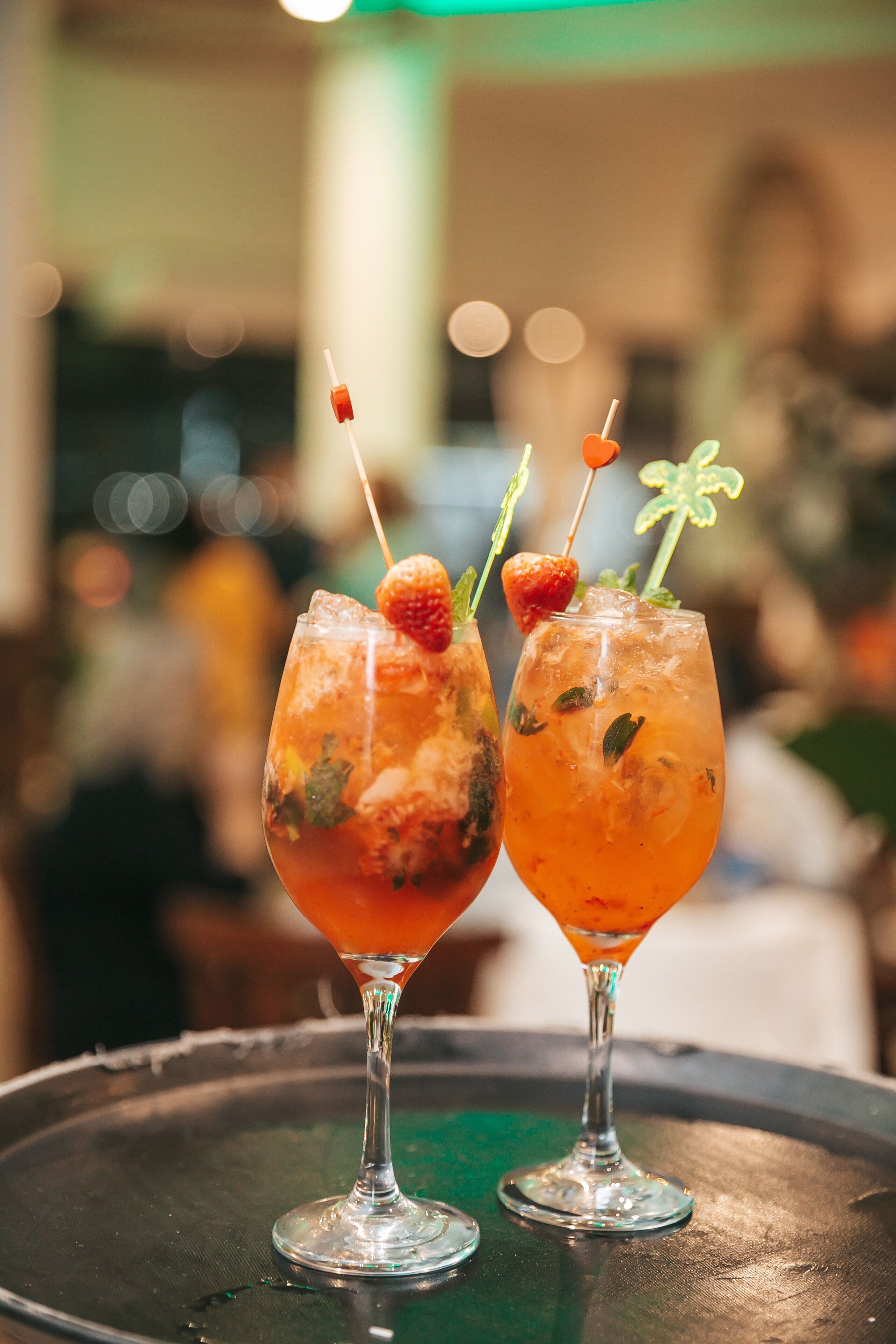 Two cocktails with garnishes on a tray.