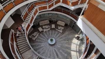A multi-level atrium with a central circular seating area, multiple staircases, and wooden paneling.