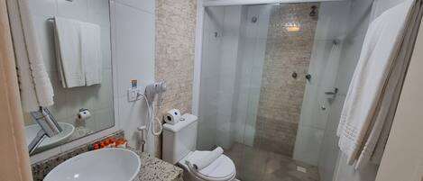 A modern bathroom with a granite countertop, a white sink, a toilet, and a glass-enclosed shower.
