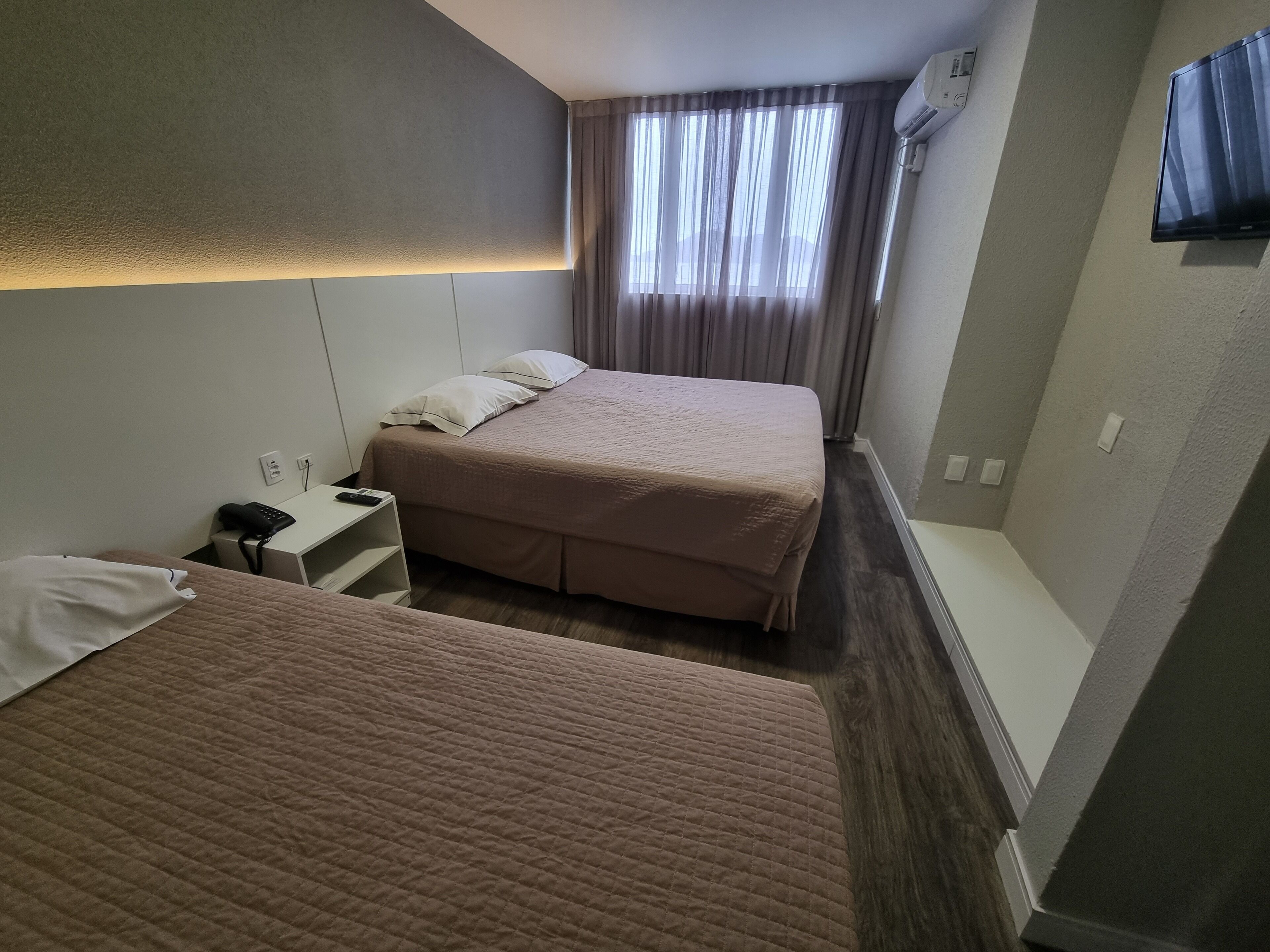 Ein Hotelzimmer mit zwei Betten, einem Schreibtisch, einem Stuhl, einem Telefon und einem Fernseher.